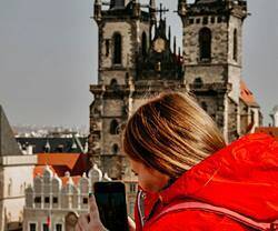 Una joven con un móvil con fondo de la iglesia de Nuestra Señora de Tyn (Praga).