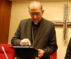 El cardenal Omella concentrado con una tablet en Conferencia Episcopal