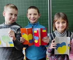 Tres niños del orfanato de Dowbysz muestran sus dibujos