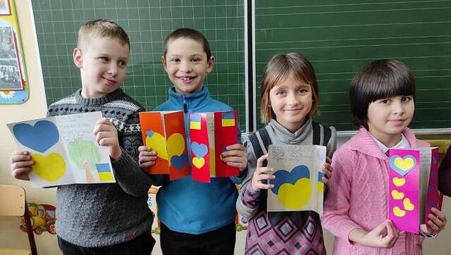Tres niños del orfanato de Dowbysz muestran sus dibujos