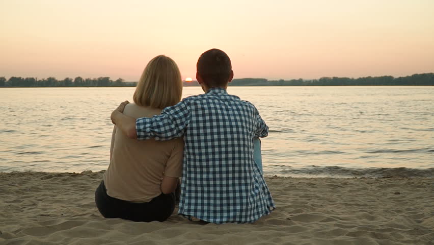 Un matrimonio en la playa miran juntos la puesta de sol