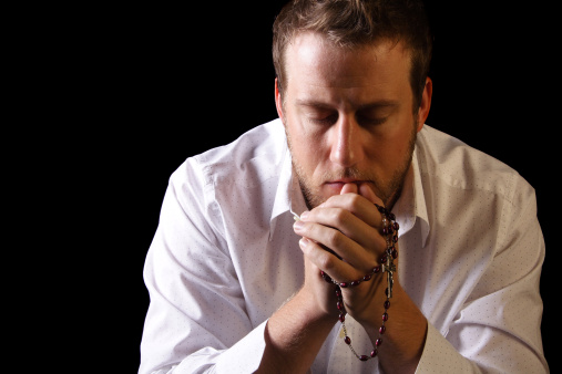 Un hombre reza el rosario