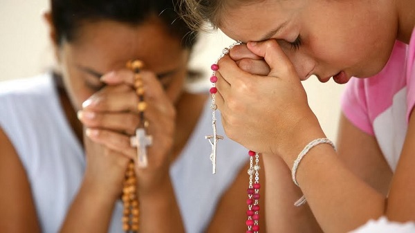 Chicas rezando el rosario.